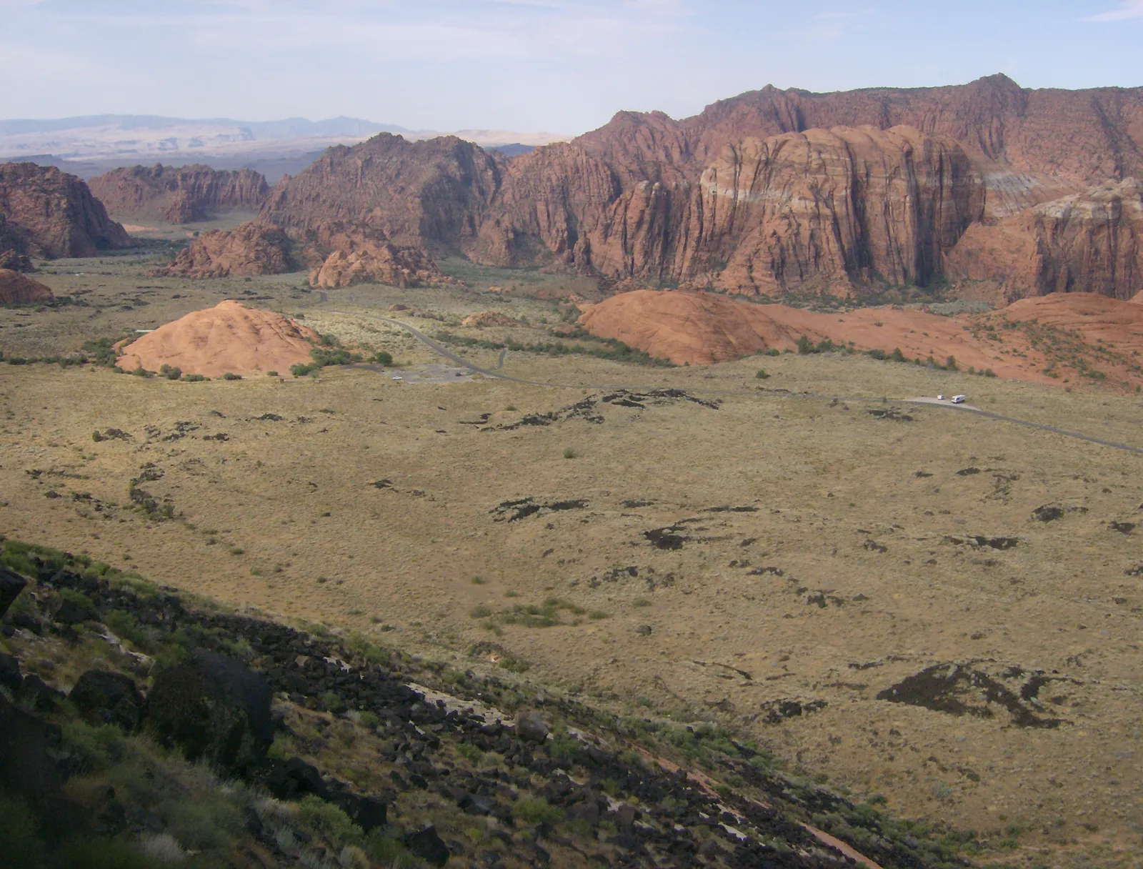 Wide view of the Snow Canyon floor with desert scrub and red and white cliffs, Snow Canyon State Park.