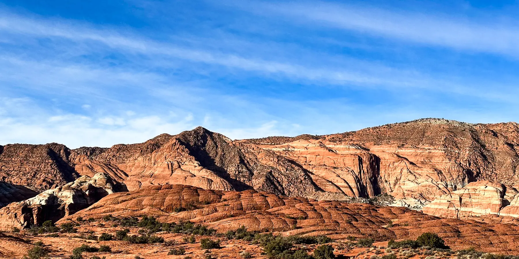 Morning light on red and white sandstone ridges above golden grass, Snow Canyon State Park.
