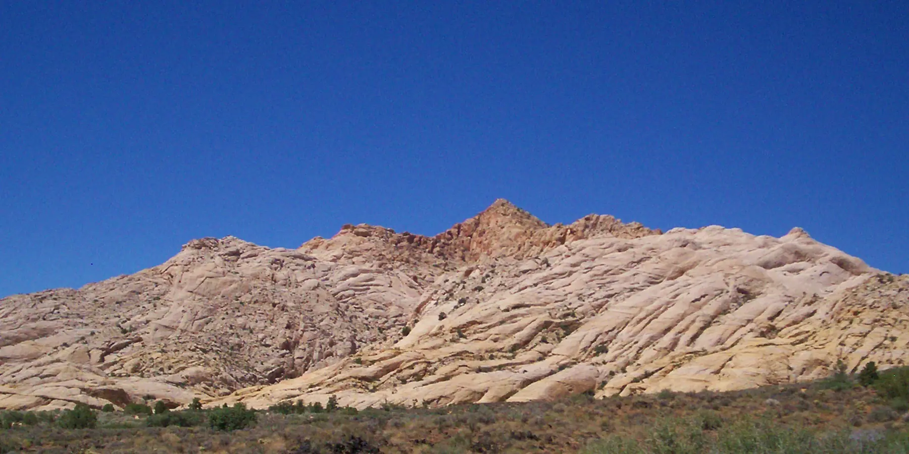 A long ridge of white Navajo Sandstone above desert scrub in Snow Canyon State Park.